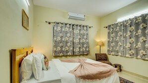 A bedroom with a bed, a chair, an air conditioner, and curtains. - Alaya Stays Saffron Breeze 4 BHK Apt (Bengaluru)
