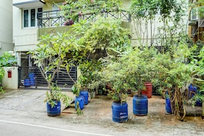 Edificio residencial con varios balcones, plantas en macetas y una entrada protegida por un portón.