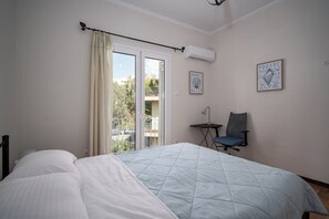 Une chambre à coucher avec un lit, une chaise, une petite table et une porte-fenêtre donnant sur un balcon.