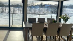 A dining area with a table, chairs, laptops, and a view of a snowy landscape through large windows. - Room-serene Guest Room Escape in Asker, (Asker)