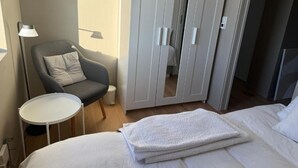 A hotel room with a bed, a chair, a small table, and a wardrobe. - Room-serene Guest Room Escape in Asker, (Asker)