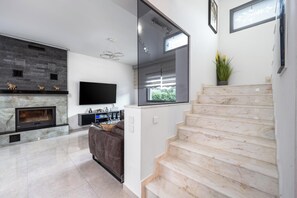 A modern living room with a fireplace, a flat-screen TV, a sofa, and a staircase. - Hideaway Villa in Ialysos (Ialysos)