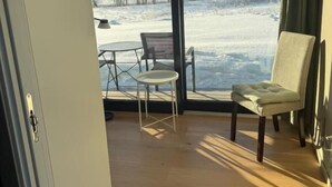 Una habitación con un ventanal grande, una silla y una mesita.