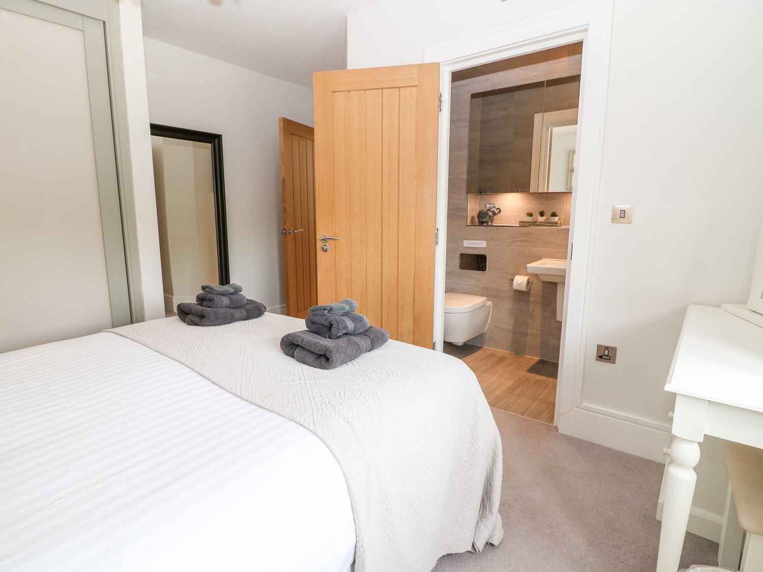 A bedroom with a bed, a wooden door, and a bathroom visible through an open door.