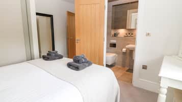 A bedroom with a bed, a wooden door, and a bathroom visible through an open door.