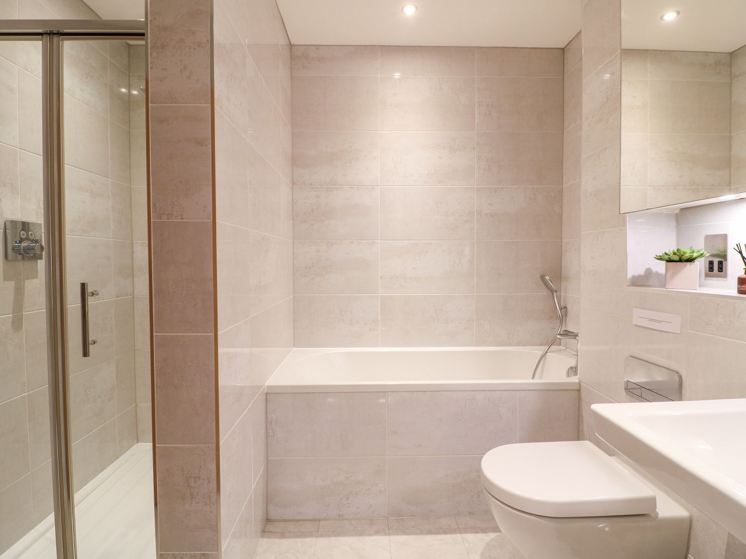 Un baño moderno con cabina de ducha de vidrio, bañera y retrete.