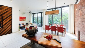 A modern kitchen with a wooden countertop, red chairs, and a dining area with large windows. - ELIVAAS 3 BHK With Private Pool and Gazebo | Terraces Villa Luxe (Marra)