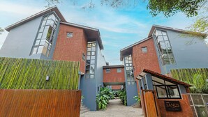 A modern building with a central entrance, large windows, and a sign indicating a hotel. - ELIVAAS 3 BHK With Private Pool and Gazebo | Terraces Villa Luxe (Marra)