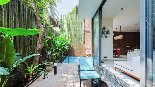 A modern outdoor patio with a seating area, a swimming pool, and a view of the interior. - ELIVAAS 3 BHK With Private Pool and Gazebo | Terraces Villa Luxe (Marra)