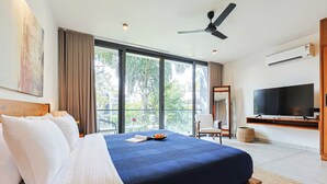 A modern hotel room with a large bed, a flat-screen TV, and a balcony with a view of greenery. - ELIVAAS 3 BHK With Private Pool and Gazebo | Terraces Villa Luxe (Marra)