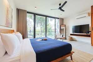 A modern hotel room with a large bed, a flat-screen TV, and a balcony with a view of greenery. - ELIVAAS 3 BHK With Private Pool and Gazebo | Terraces Villa Luxe (Marra)