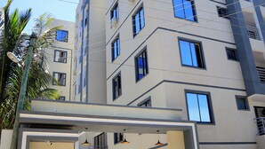 A multi-story building with a gated entrance, balconies, and a sign indicating 'CORAL SANDS LUXURY APARTMENTS.'