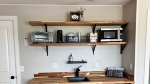 A kitchen with wooden countertops, a built-in microwave, a toaster, and a refrigerator.