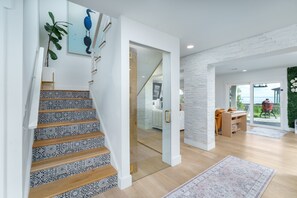A staircase with patterned tiles, a view into a room with a desk and chair, and a view through a glass door to an outdoor area. - THE BAYFRONT HAVEN Private Dock Sauna Pet-Friendly Luxury Destin 30A Retreat (Santa Rosa Beach)