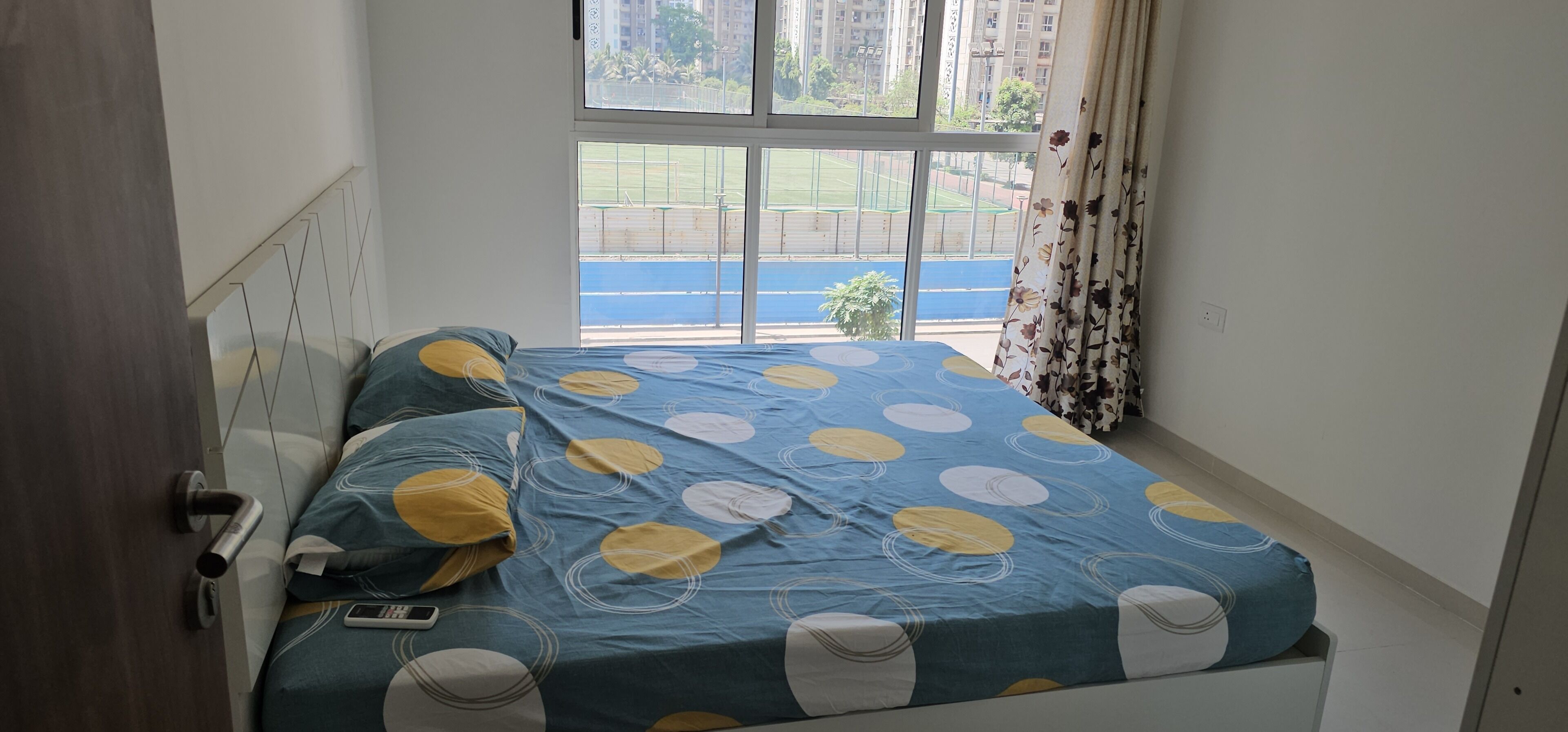 A bedroom with a bed, a window, and a view of a sports field.
