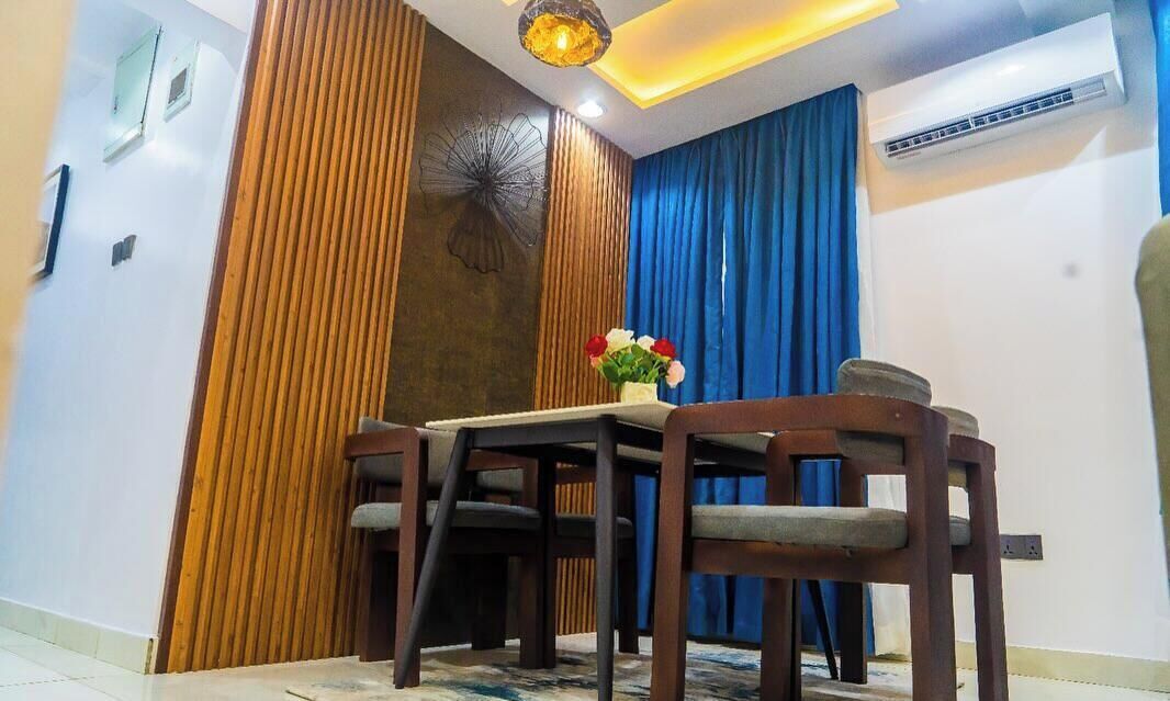 A dining area with a table and chairs, a decorative wall panel, and an air conditioning unit.