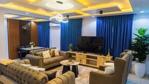 A modern living room with a sofa, coffee table, TV, and curtains. - THE 81 APARTMENTS (Lagos)