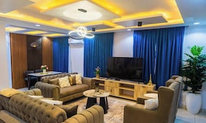 A modern living room with a sofa, coffee table, TV, and curtains. - THE 81 APARTMENTS (Lagos)
