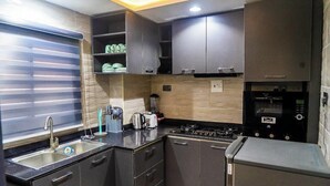 A compact kitchen with a sink, stove, and built-in oven. - THE 81 APARTMENTS (Lagos)