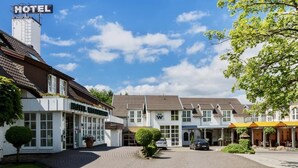 A hotel with a sign, a paved driveway, and a row of buildings. - Hotel Waldesrand (Herford)