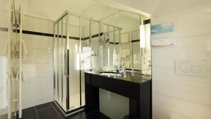 Une salle de bain moderne avec une douche à parois de verre, un meuble-lavabo noir et un grand miroir.