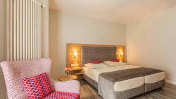 Habitación de hotel con cama, una silla, una mesita de noche y un radiador fijado a la pared.
