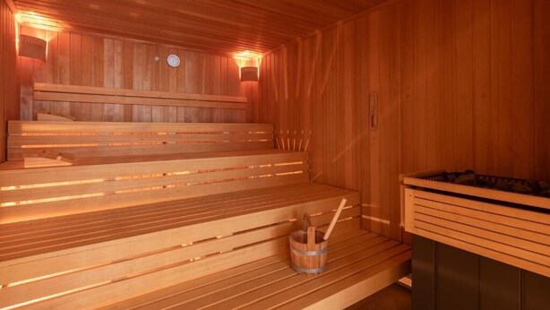Un sauna en bois avec des bancs et un seau.