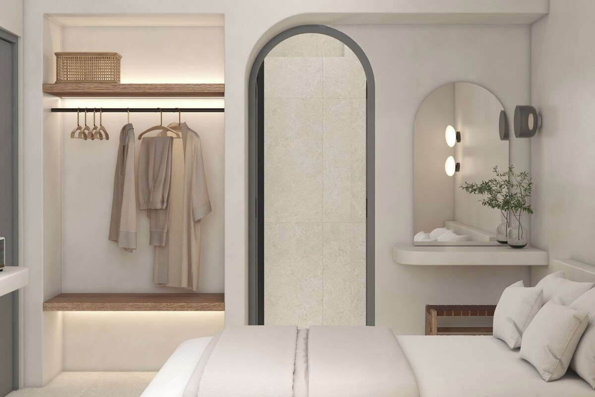 A modern bedroom with a bed, a vanity with a mirror and lights, a hanging robe rack, and a small shelf.