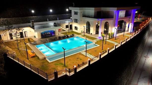 Ein Hotel mit Swimmingpool, Außenbereich und einer Steinmauer.