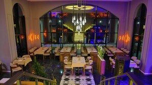 Ein Restaurant mit mehreren Tischen, Stühlen, einer Kristallleuchter und einer Treppe.
