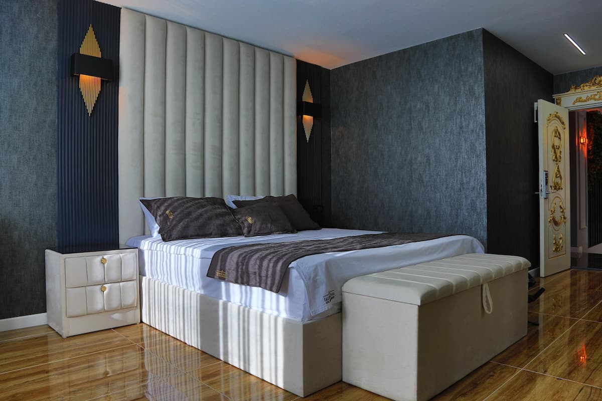 A modern bedroom with a large bed, bedside tables, and a wardrobe.