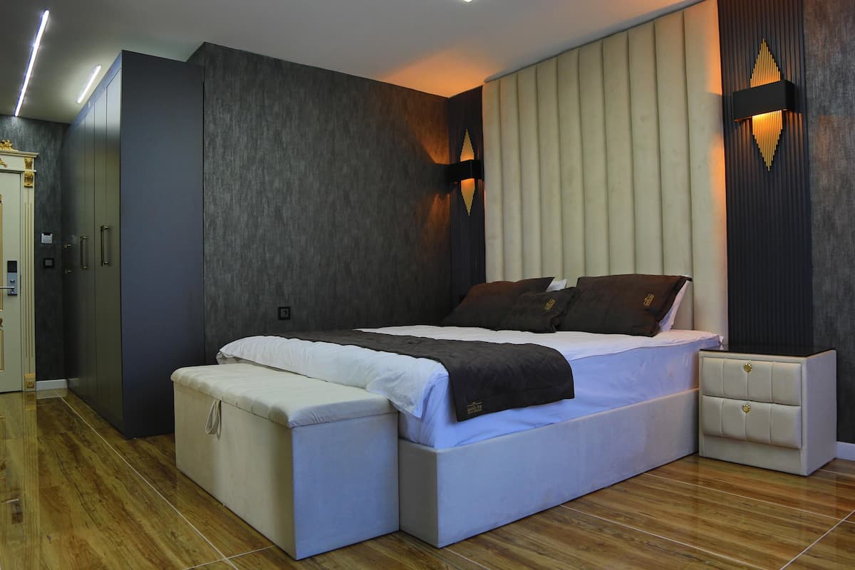 A modern bedroom with a large bed, bedside tables, and a wardrobe.