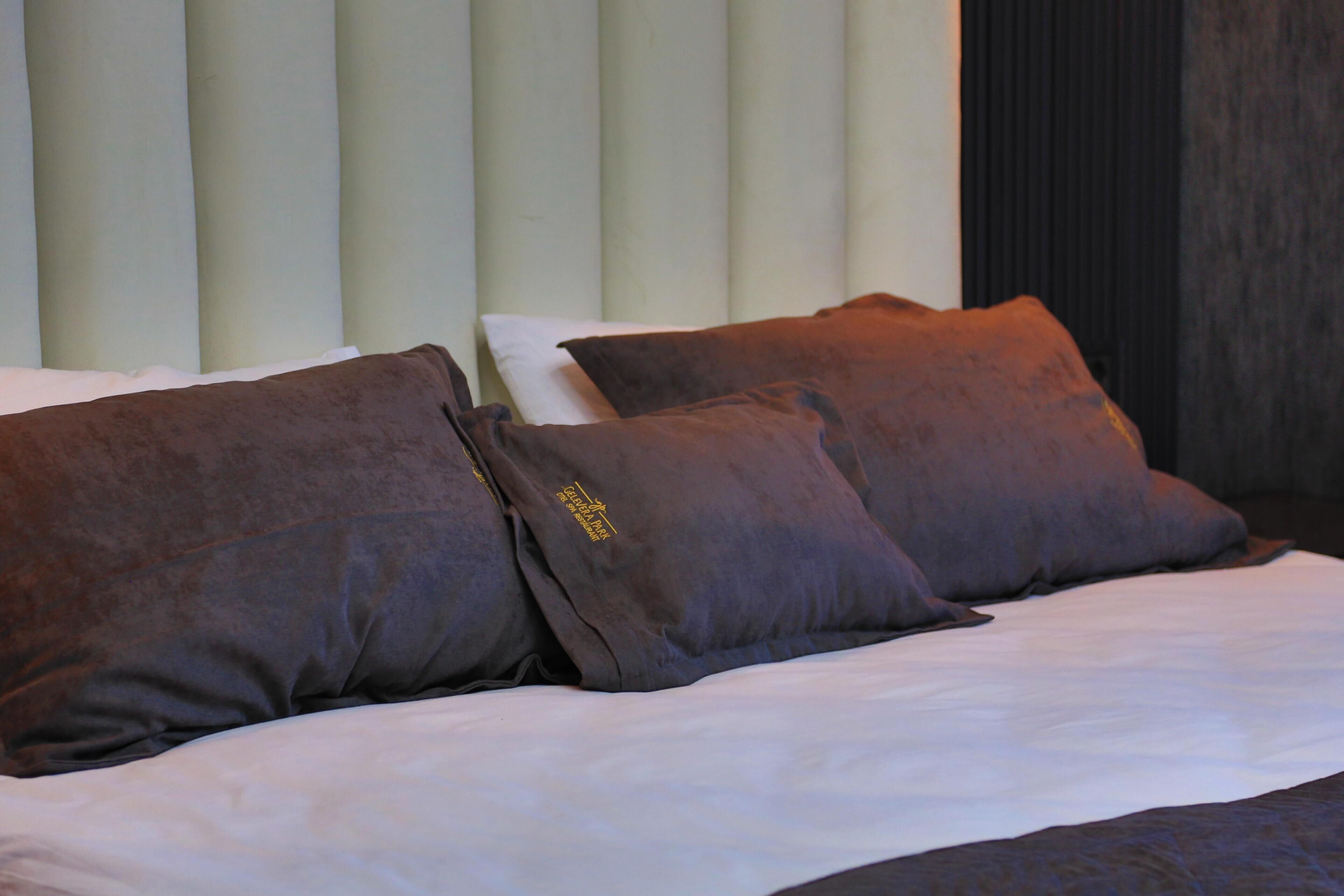 Una cama con ropa de cama blanca y dos almohadas marrones.