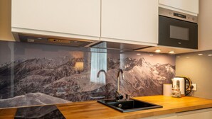 A modern kitchen with a granite countertop, stainless steel sink, and a built-in oven. - ANAapart (Zakopane)