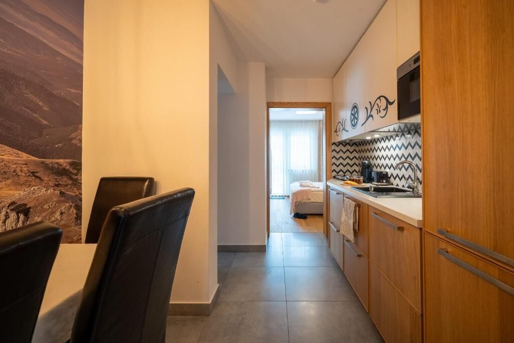 A modern kitchen with wooden cabinets, a microwave, and a patterned backsplash.