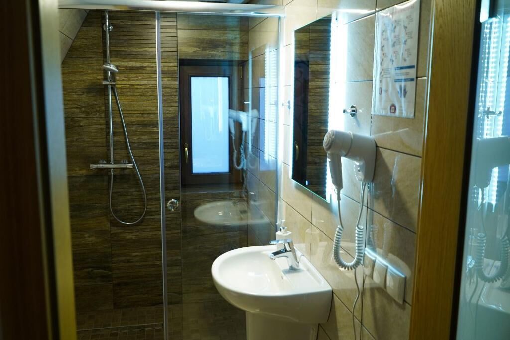 A modern bathroom with a glass-enclosed shower, a sink, and a telephone.