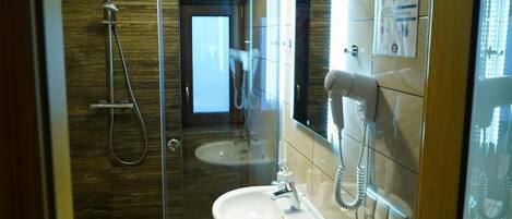 A modern bathroom with a glass-enclosed shower, a sink, and a telephone.