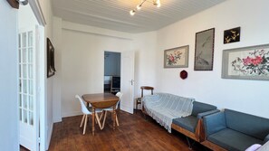 Ein Zimmer mit einem Holztisch, einem blauen Sofa und einem weißen Stuhl.