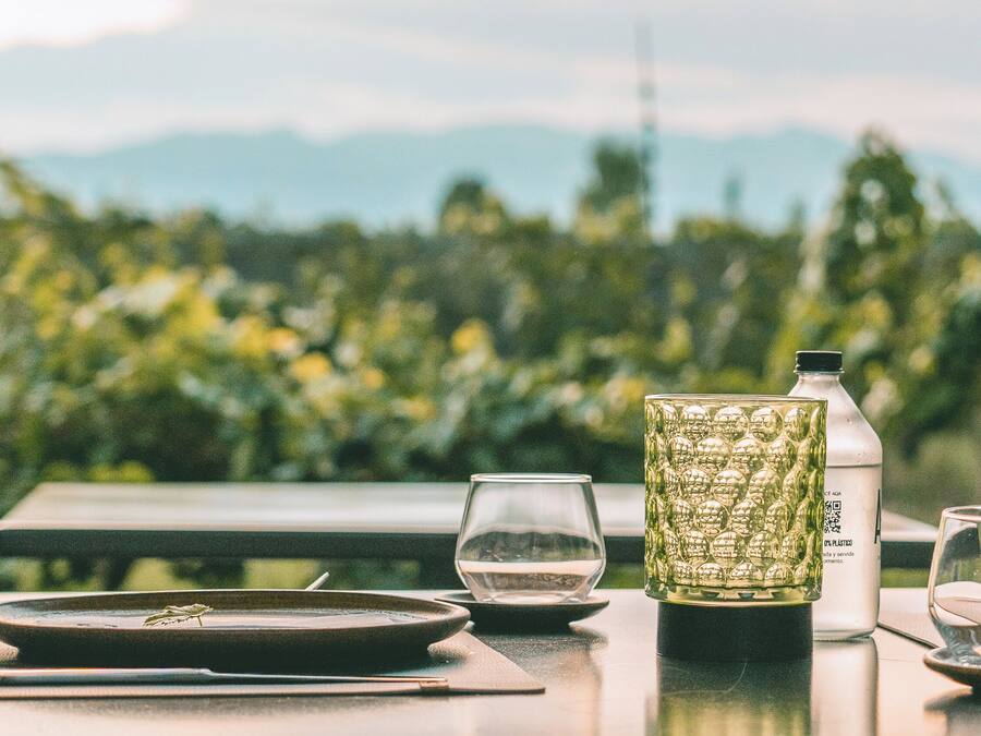 A table with a plate, a glass, a bottle, and a decorative glass container.