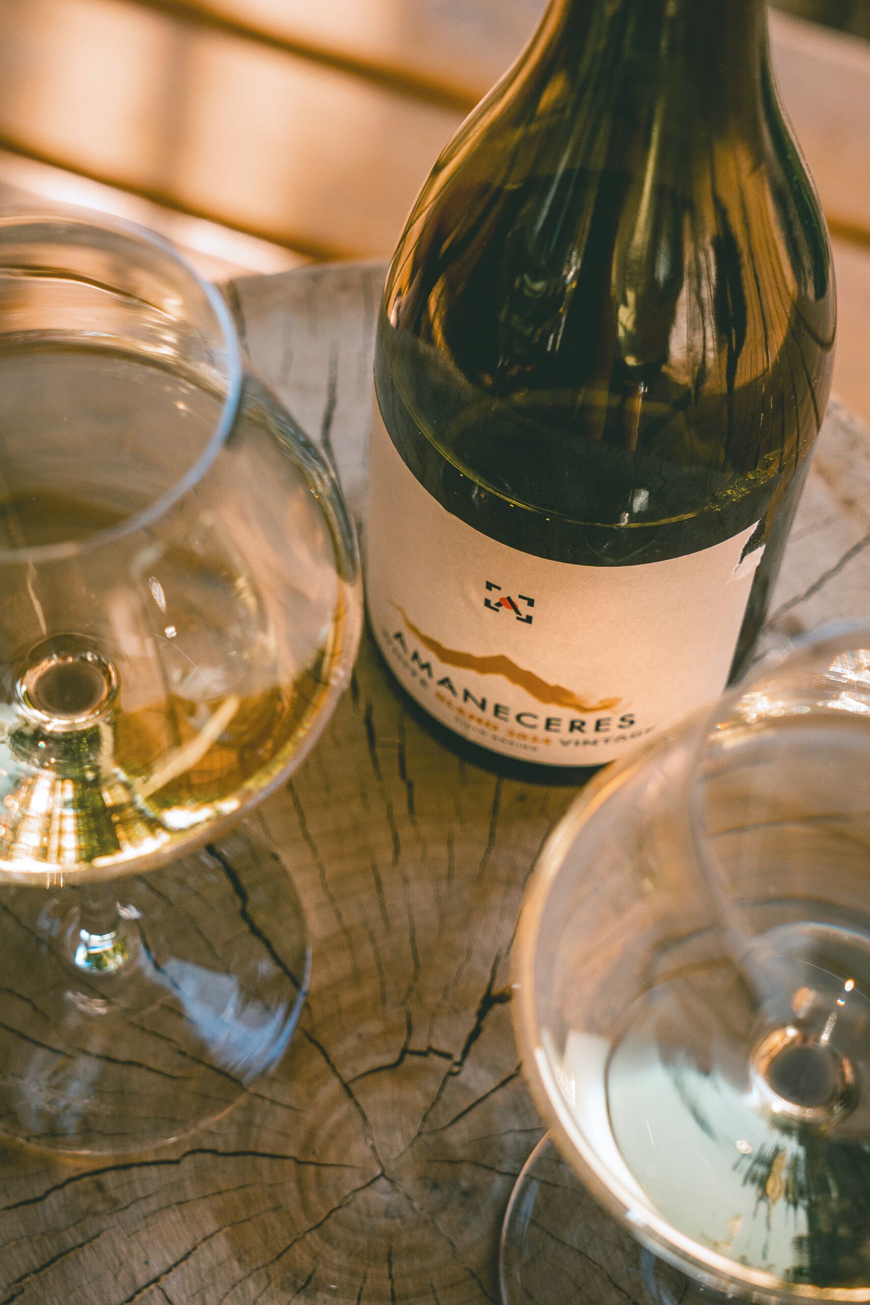 A wine bottle with a label, two empty wine glasses, and a wooden surface.
