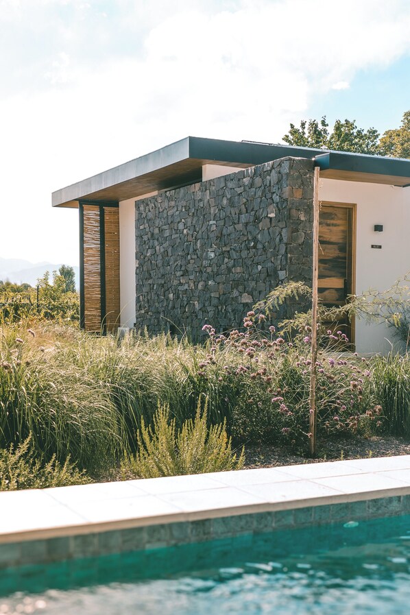 A modern house with a stone facade, a pool, and a view of the mountains. - Boutique Hotel Bodega CICLO ANDINO (Lujan de Cuyo)