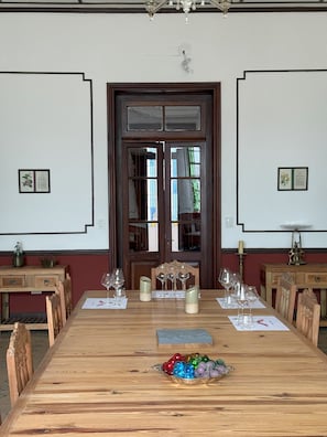 A dining room with a wooden table set for a meal, flanked by wooden chairs, a chandelier, and framed botanical prints on the walls.