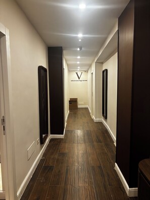 Un pasillo con suelo de madera, paredes blancas y un letrero que dice 'VATICAN BOUTIQUE ROOMS'.