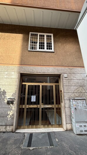 A building entrance with a large metal gate, a small window above the gate, and a number '20' on the wall. - Vatican Boutique Rooms (Rome)
