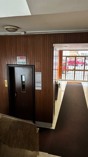 A hotel lobby with a wooden panel wall, a reception desk, and a glass door leading outside. - Vatican Boutique Rooms (Rome)