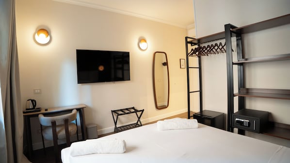 A hotel room with a bed, a desk, a chair, a television, a mirror, and a coat rack. - Vatican Boutique Rooms (Rome)