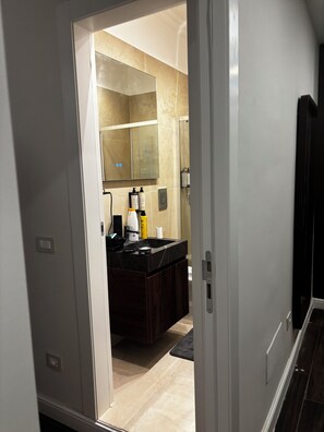 Un baño moderno con un tocador oscuro, un espejo grande y una zona de ducha.