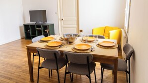 Un coin repas avec une table dressée pour quatre personnes, des chaises, un téléviseur et une porte.