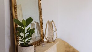 Une pièce avec un grand miroir, une plante en pot, une bougie et une petite table.