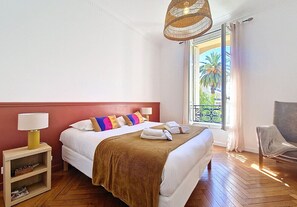 Ein Hotelzimmer mit Bett, Nachttisch, Lampe und Blick ins Freie.